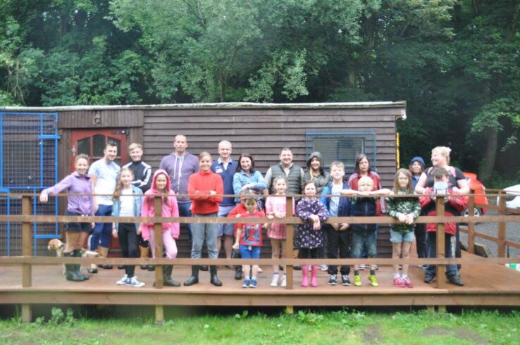 Sunnyvale Outdoor Centre Image of all age groups of volunteers outside a wooden cabin